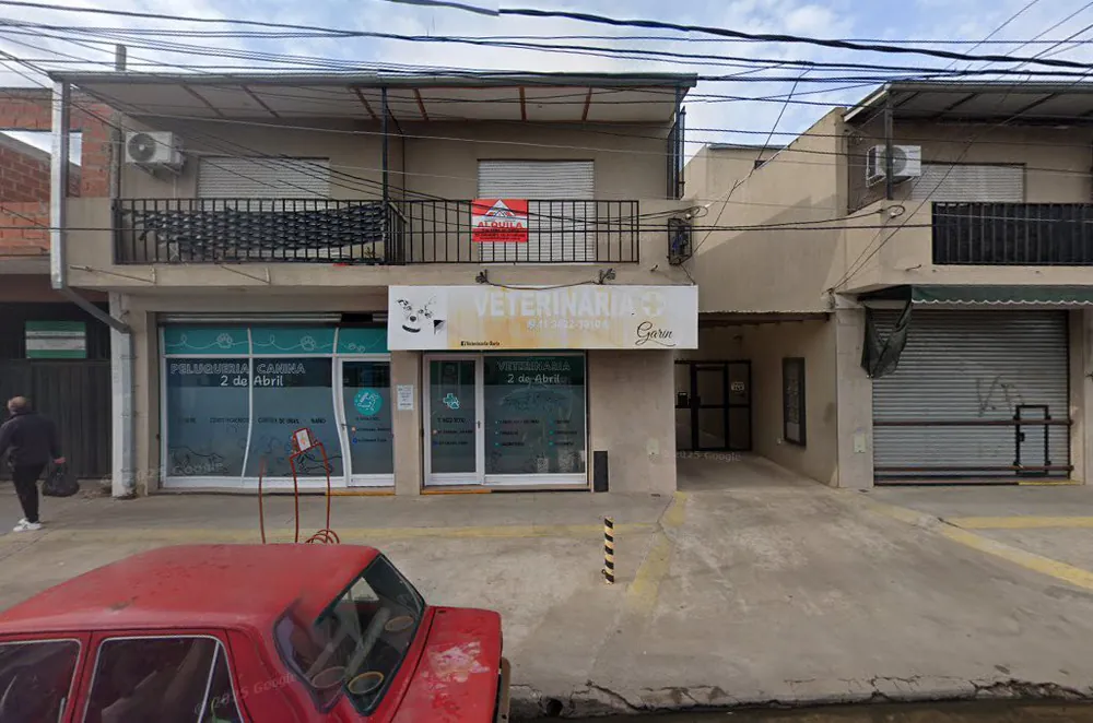 Frente de la veterinaria: vidriera verde agua con la cruz y la huella, debajo del cartel que dice Veterinaria